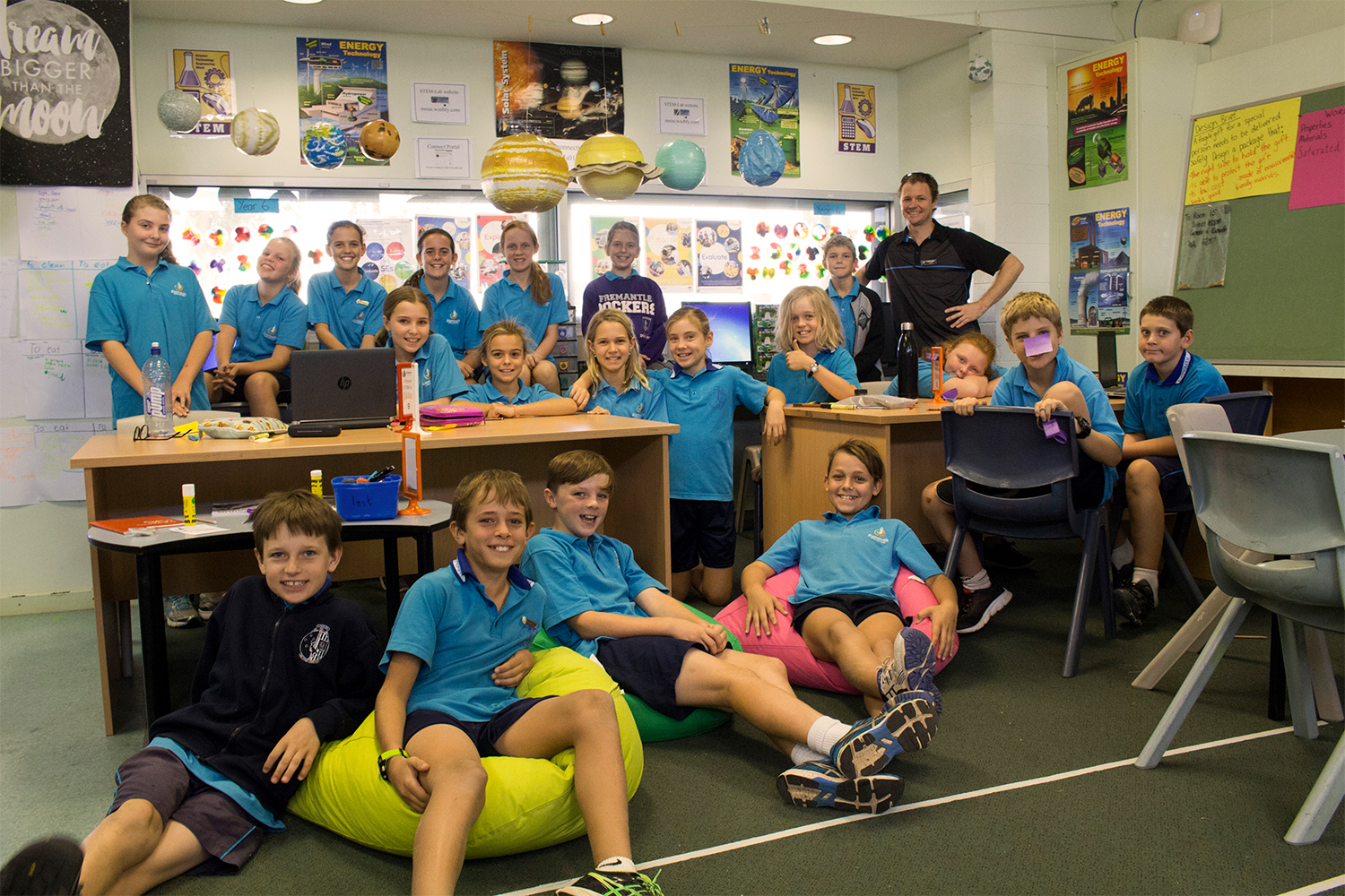 Kids in a classroom, looking at the camera and posing up a storm.