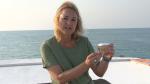 Monika Schlacher-Hoenlinger holding a jar containing soft coral, sitting on the back of a boat  