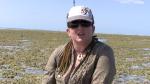 Zoe Richards wearing a hat and sunglasses talking about the corals on a reef  