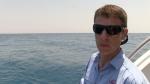 Dr Glenn Moore fishing from the back of the Kimberley Quest boat wearing sunglasses  