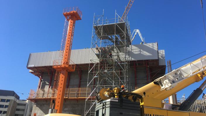 Building site with scaffolding siting against a concrete box with a crane