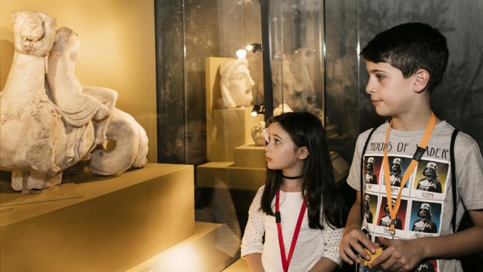 Caption: Educator Preview: Escape from Pompeii "Two children look at an artefact from the exhibition with great curiosity."