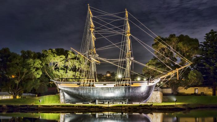 The Brig Amity at night. "The Brig Amity at night. Its reflection can be seen in the water."