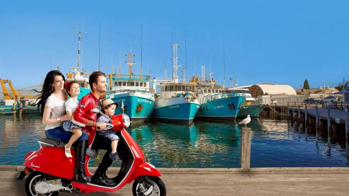 Caption: Little Italy by the Sea "A family ride a Vespa on a jetty"