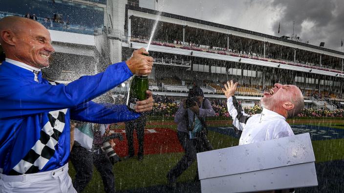 Caption: Champagne Shower. “Two jockeys are celebrating a victory by popping a bottle of champagne.”
