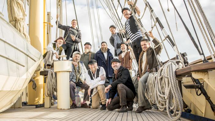 The Lost Quays 11 men grouped on a ship's deck, dressed in seafaring ware.