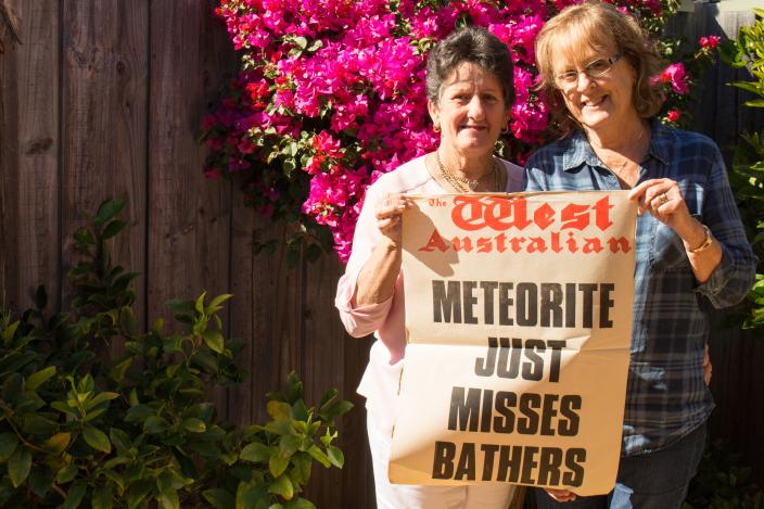 two women hold up newspaper headline reads meteorite just misses bathers