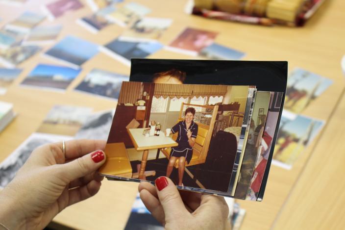 hands holding a photograph of a woman in a diner 