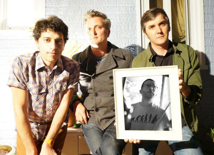 Band photo shows Adem, Todd, and Paul,with Paul holding a photo of Dean