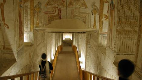 Two tourists walking through the corridors of the tomb of an ancient Egyptian pharaoh