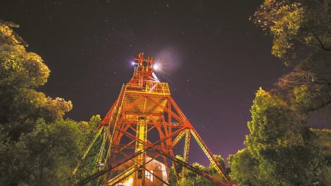 Caption: The Museum of the Goldfields. "An upwards shot of a orange tower at night, with the moon glowing behind it."