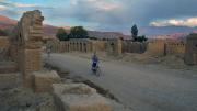 A boy riding a bike down an ancient road