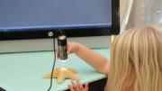 a small girl examines a sea shell using a microscopic camera