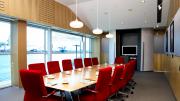 Maritime Museum Kailis Family Boardroom Sixteen red chairs around a boardroom table with views of the harbour through windows on one side