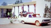 People pack a ute outside an American style building made of brick with a flat roof.