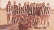 Women in black and white Australian rules jersey's pose for a team photo