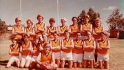 A team young boys football team pose for a team photo, they wear white shorts and yellow jerseys