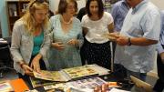 Four people huddle around the Memory Book looking at photographs and discussing