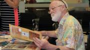 Older man sits and looks through memory book created by Exmouth residents