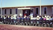 A ceremony at the US Naval base in Exmouth, a row of seated people observe a  uniformed naval offices at a podium.