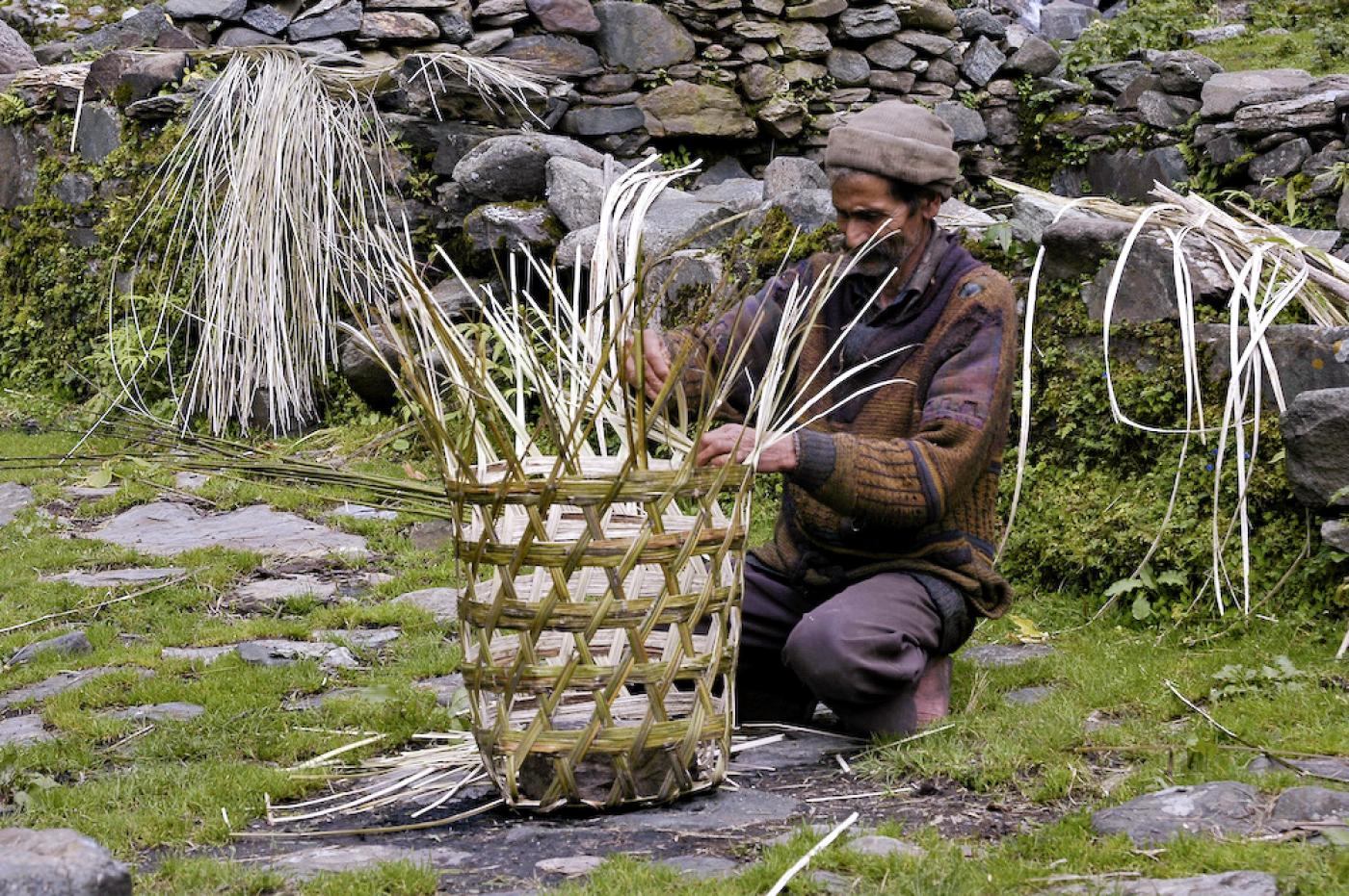 An Indian man creating a basket with a Seven-Step Caning design.