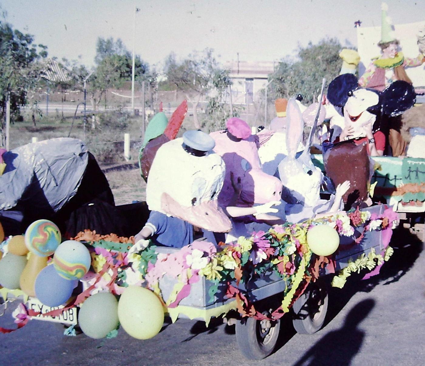 Children in Looney Tunes costumes sit in the back of a decorated trailer 