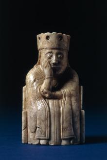 A queen from the Lewis Chess set sitting on a throne with her head in her hand