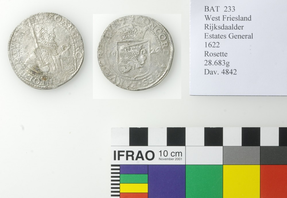 Two sides of a silver coin recovered from the Batavia Shipwreck placed next to a standard colour guide