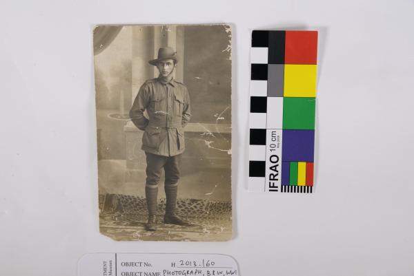 PHOTOGRAPH, B&W, WWI studio portrait of Matthew Harwood, AIF, standing in uniform. Silver fish damage.