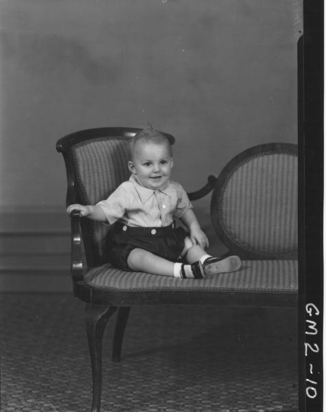 Portrait of boy in shirt and shorts, F/L,'Jordon', sitting on end of settee.