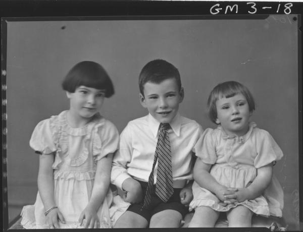 portrait of two young girls in dresses and young boy in shirt and tie, sitting on cushioned bench, 3/4,'Illingworth'.