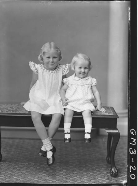 Portrait of two young girls, F/L, 'Jenson'. In dresses, sitting on cushioned bench.
