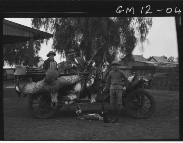 Three men in open car with their catch of Wild Turkeys, 'Duff'