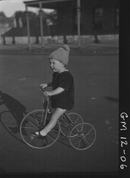 Street view of young child riding a tricycle, F/L 'Dunstan'