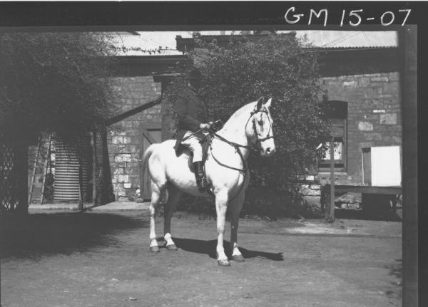 man in riding costume on horse outside stone house, 'Hill'