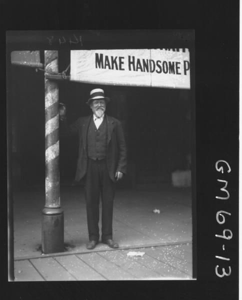 OLD MAN STANDING OUTSIDE SHOP