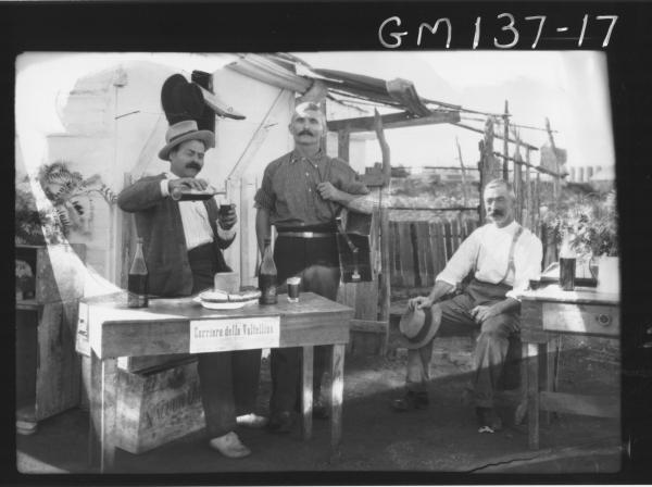 Three men outside camp wine tasting