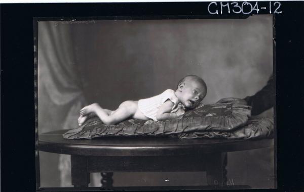 F/L Portrait of baby lying on table wearing knitted top; 'Rawlins'