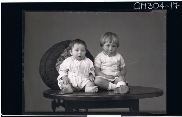 F/L Portrait of baby seated on table, and a child seated also,wearing short lace dress; 'Smythe'