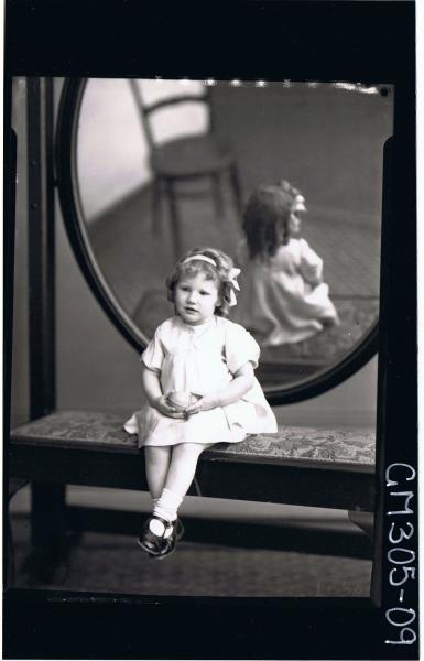 F/L Portrait of girl child seated in front of mirror wearing short dress, ribbon in hair holding a ball; 'McCormack'