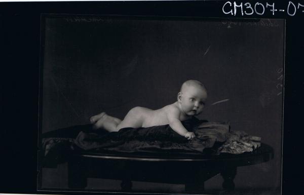 F/L Portrait of naked baby lying on table; 'Schliker'