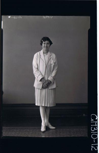 F/L Portrait of woman standing, wearing knee length pleated dress and jacket; 'Song'