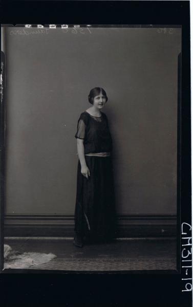 F/L Portrait of woman standing, wearing ankle length dress with sash around hips 'Saunders'