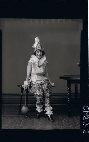 F/L Portrait of woman seated, wearing clown fancy dress costume, holding balloon on string 'Slee'
