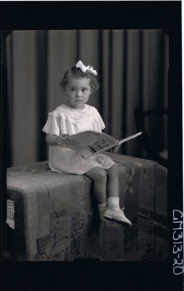 F/L Portrait of girl child seated, wearing short dress, ribbon in hair holding a book 'Cerinich'