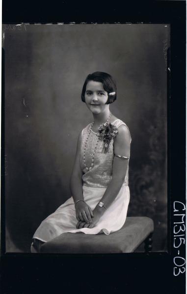3/4 Portrait of woman seated, wearing satin knee length dress corsage on shoulder 'Mitchell'