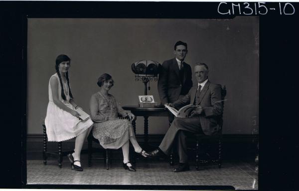 F/L Family Portrait of a man and woman seated, man holding a book, young woman and young man seated on table 'Murray'