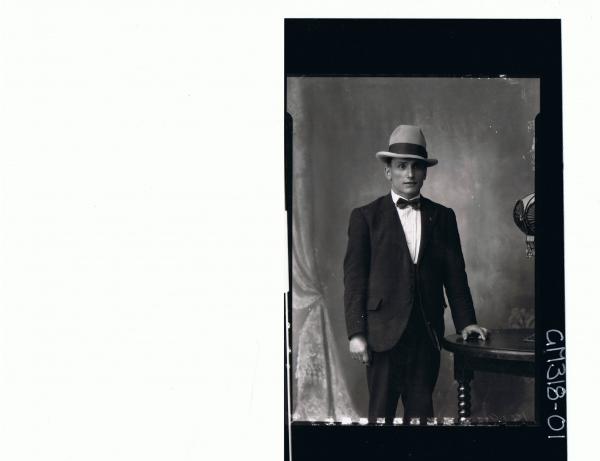 3/4 Portrait of man standing wearing suit, bow tie, hat; 'Nouchey'