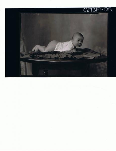 F/L Portrait of baby lying on table wearing vest 'Summer'