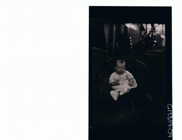 F/L Portrait of baby seated in garden with water tanks and buildings in bgrd. 'Smith'